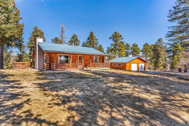 log home with an outbuilding, a chimney, covered porch, metal roof, and log siding