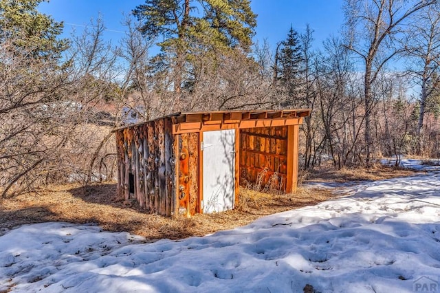 snow covered structure featuring an outbuilding