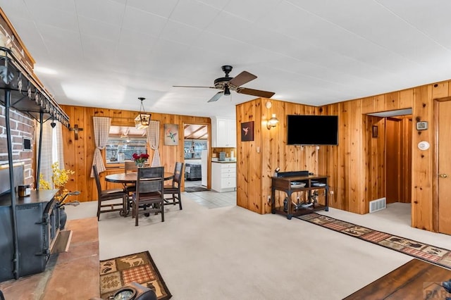 dining room featuring wooden walls, a healthy amount of sunlight, light carpet, and visible vents