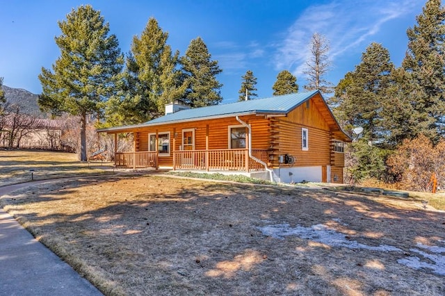 log home with metal roof, a porch, a garage, log siding, and a chimney