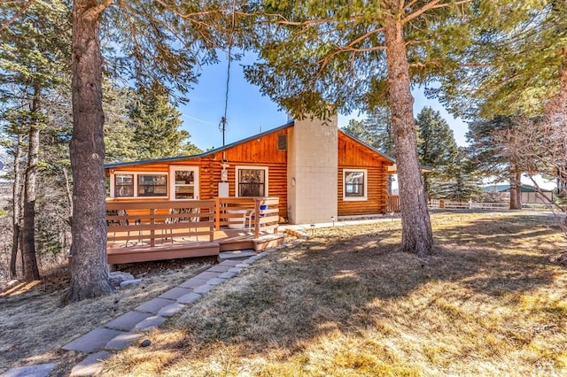 back of house with a deck, a yard, a chimney, and log siding