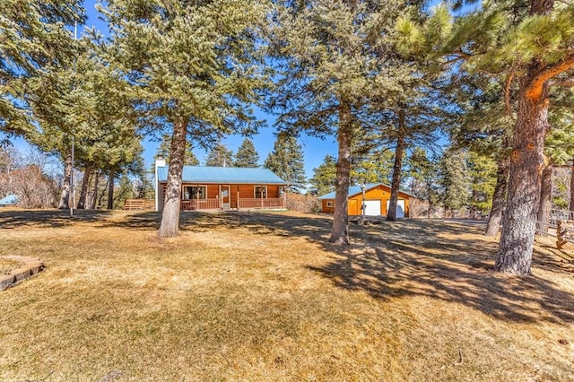 view of front of property featuring covered porch, metal roof, a front yard, and an outbuilding