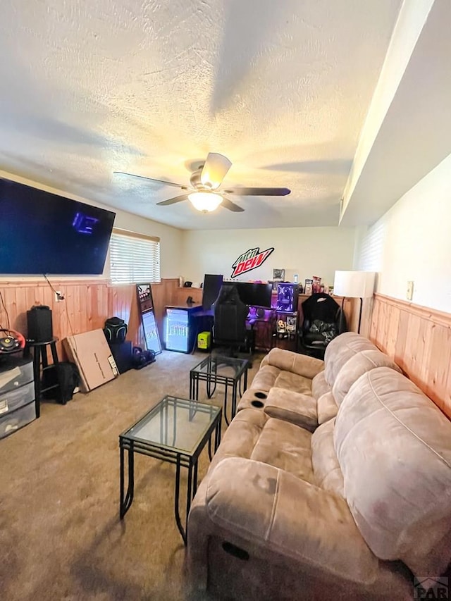 1320 Bradish Ave, La Junta, CO 81050 - living area featuring wooden walls, a textured ceiling, a ceiling fan, a wainscoted wall, and carpet flooring
