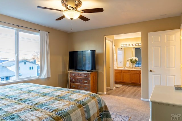 bedroom featuring connected bathroom, a ceiling fan, baseboards, and light carpet