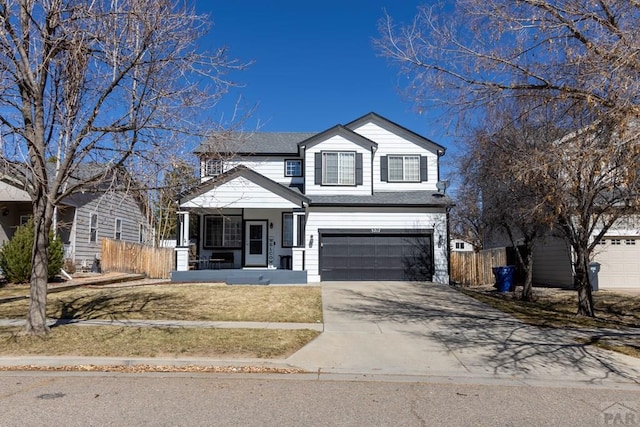 traditional home featuring a garage, a porch, concrete driveway, and fence