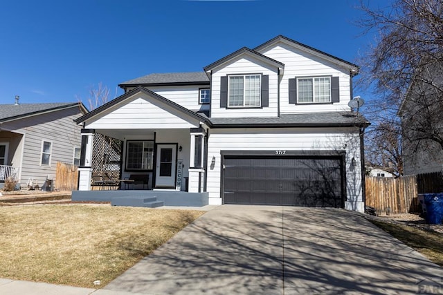 traditional-style house featuring a front yard, fence, driveway, covered porch, and a garage