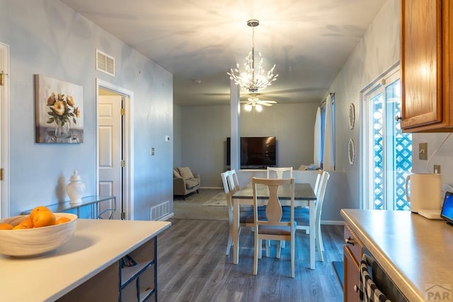 dining area with visible vents, ceiling fan with notable chandelier, baseboards, and dark wood-style flooring