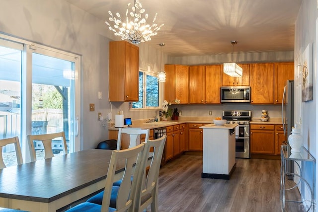 kitchen featuring a center island, dark wood-style flooring, an inviting chandelier, stainless steel appliances, and a sink