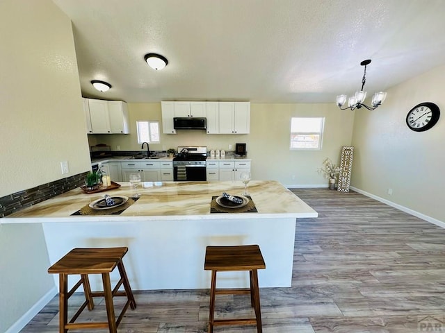 kitchen featuring a peninsula, appliances with stainless steel finishes, hanging light fixtures, and a kitchen breakfast bar