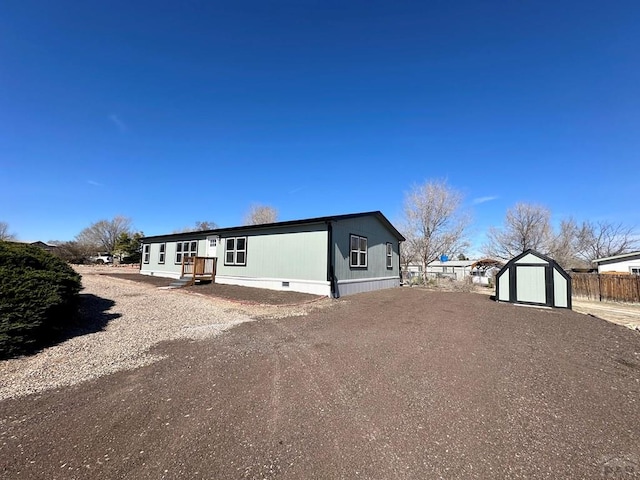 view of front of house featuring an outbuilding, a storage shed, crawl space, fence, and driveway