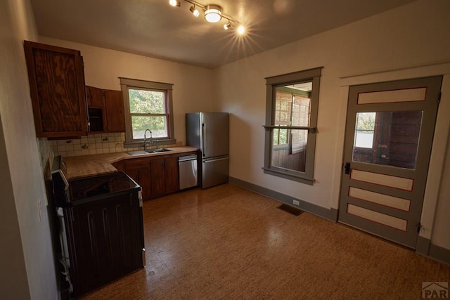 315 S Oak St, Trinidad, CO 81082 - kitchen with appliances with stainless steel finishes, light flooring, a sink, tasteful backsplash, and baseboards