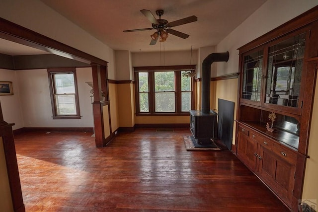 315 S Oak St, Trinidad, CO 81082 - unfurnished living room with a wood stove, dark wood-style floors, ceiling fan, and baseboards