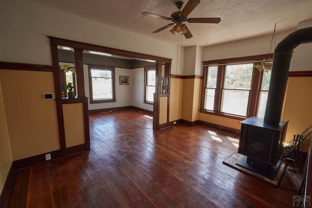 315 S Oak St, Trinidad, CO 81082 - unfurnished living room with dark wood finished floors, baseboards, a ceiling fan, a wood stove, and a textured ceiling