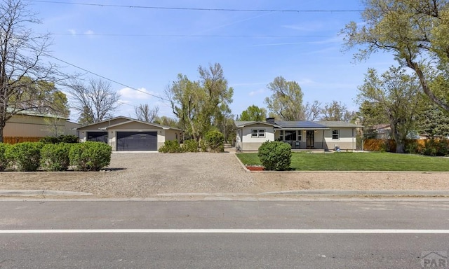 4321 Goodnight Ave, Pueblo, CO 81005 - ranch-style house with a garage, driveway, a front yard, and solar panels