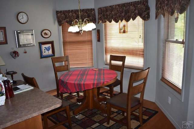 dining area featuring baseboards, a chandelier, and wood finished floors