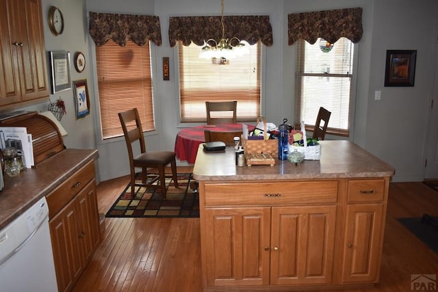 kitchen with a kitchen island, brown cabinets, white dishwasher, and hanging light fixtures