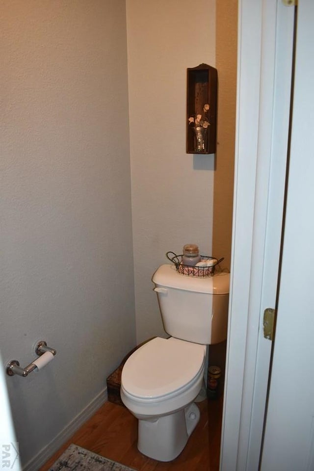 bathroom with baseboards, toilet, and wood finished floors