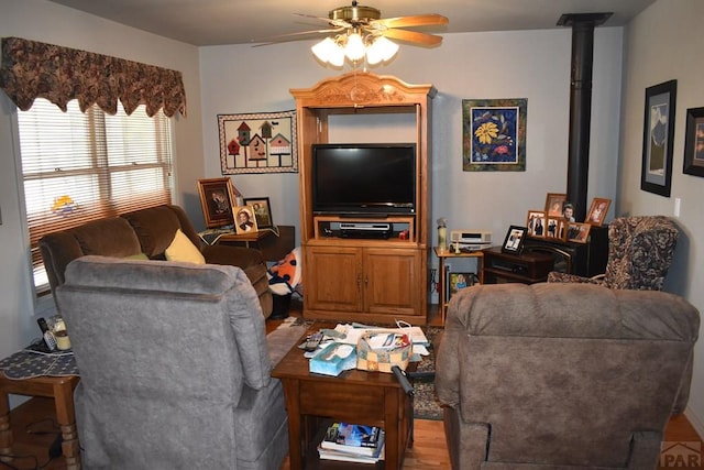 living room with a wood stove, ceiling fan, and light wood finished floors