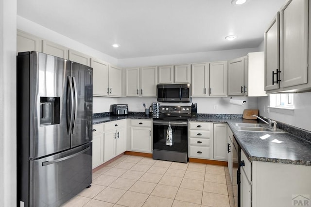 kitchen with light tile patterned floors, recessed lighting, stainless steel appliances, a sink, and dark countertops