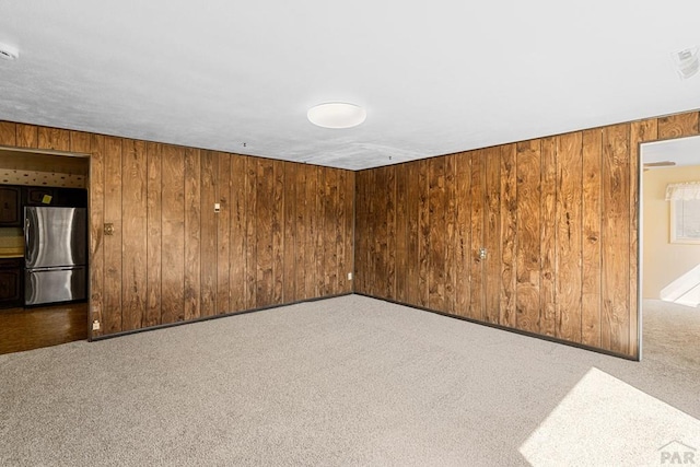 unfurnished room with wood walls and carpet