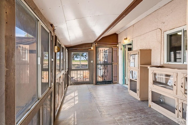 unfurnished sunroom featuring lofted ceiling with beams