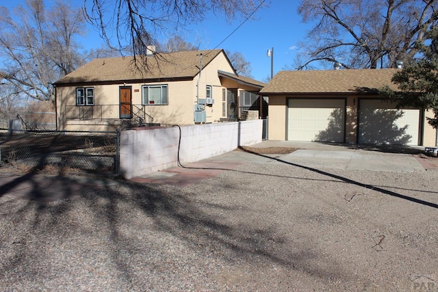 view of front of property featuring a fenced front yard, a shingled roof, a garage, and stucco siding