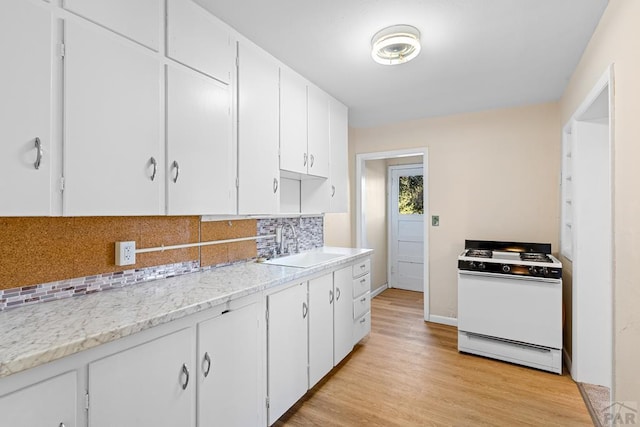 kitchen featuring white cabinets, white range with gas cooktop, decorative backsplash, and a sink