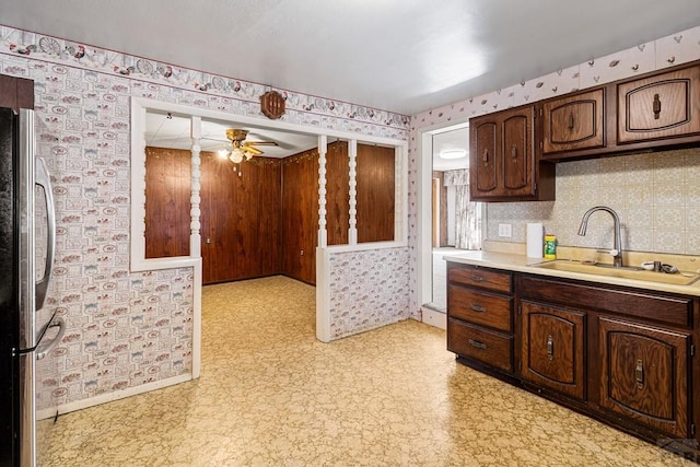 kitchen with wallpapered walls, freestanding refrigerator, light countertops, light floors, and a sink