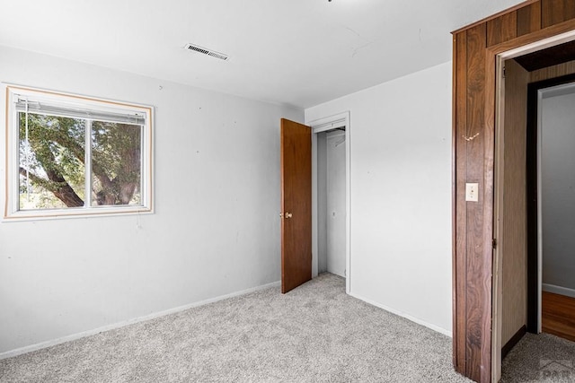 unfurnished bedroom with light carpet, a closet, visible vents, and baseboards