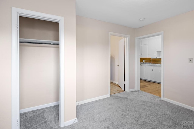 unfurnished bedroom featuring a closet, carpet flooring, connected bathroom, and baseboards