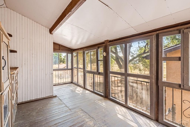 unfurnished sunroom featuring lofted ceiling with beams