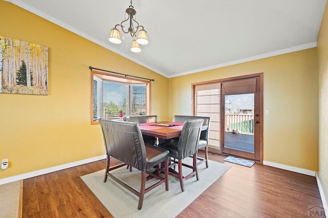 dining space featuring lofted ceiling, crown molding, wood finished floors, and baseboards