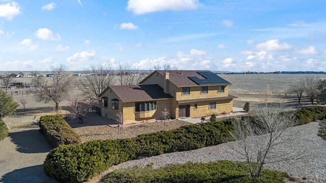 view of front of home with roof mounted solar panels and stucco siding