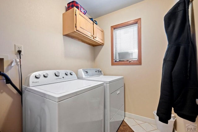 clothes washing area with cabinet space, light tile patterned floors, baseboards, and separate washer and dryer