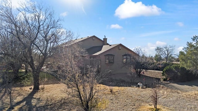 view of home's exterior with a chimney and stucco siding