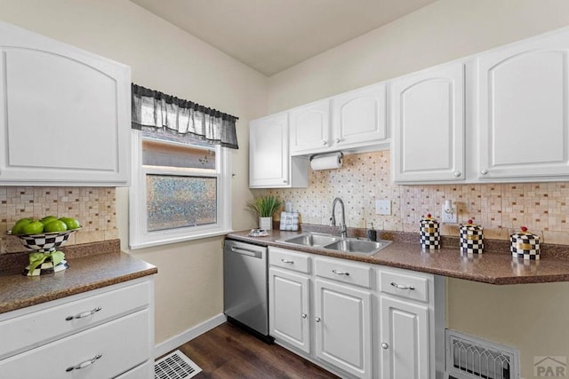 kitchen featuring dark countertops, white cabinetry, a sink, and stainless steel dishwasher