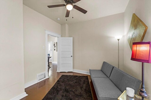 sitting room featuring a ceiling fan, visible vents, baseboards, and wood finished floors