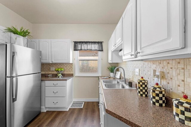 kitchen featuring dark countertops, visible vents, freestanding refrigerator, white cabinetry, and a sink