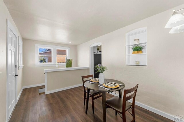 dining space featuring dark wood-type flooring and baseboards