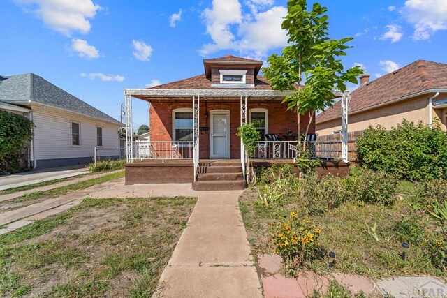 bungalow featuring a porch and brick siding