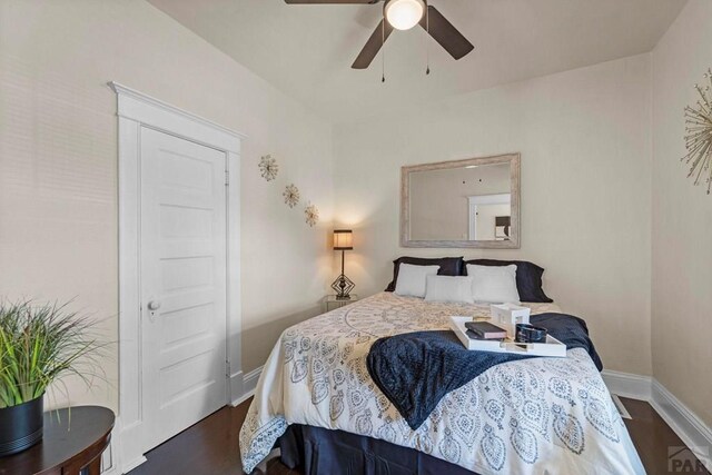 bedroom with dark wood-type flooring, a ceiling fan, and baseboards