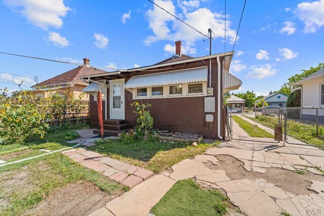 bungalow with a gate, fence, and stucco siding