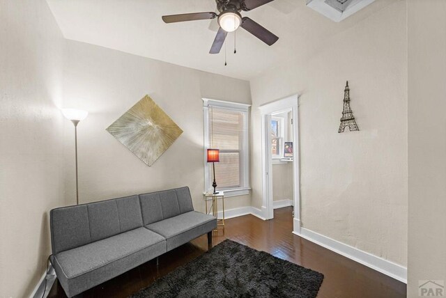 living area featuring ceiling fan, baseboards, and dark wood finished floors