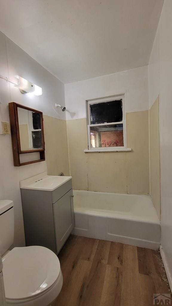 bathroom with toilet, washtub / shower combination, wood finished floors, and vanity