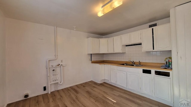 kitchen featuring decorative backsplash, white cabinetry, light countertops, and a sink