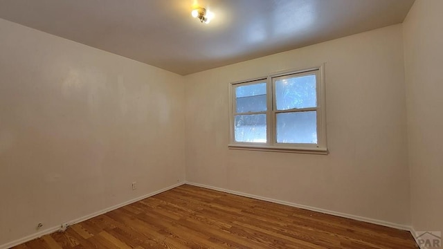 empty room with baseboards and wood finished floors