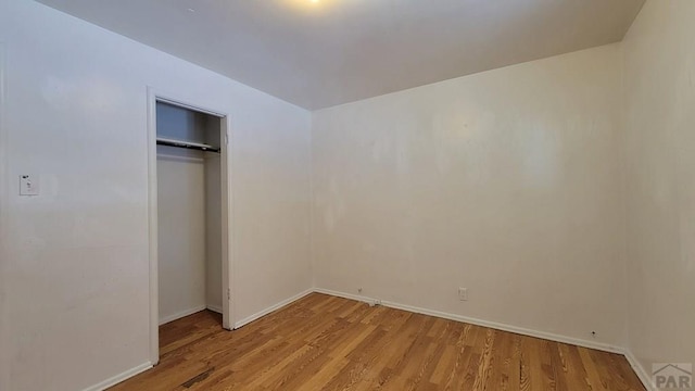 unfurnished bedroom featuring a closet, light wood-style flooring, and baseboards