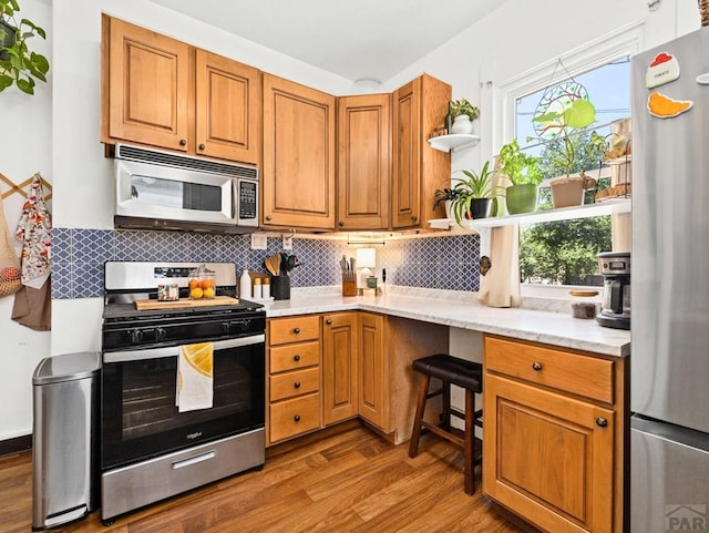 309 Quincy St, Pueblo, CO 81004 - kitchen with stainless steel appliances, open shelves, light wood-style floors, tasteful backsplash, and plenty of natural light