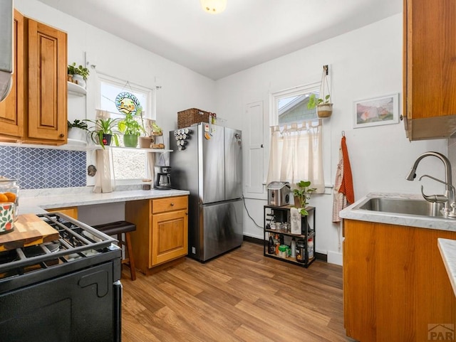 309 Quincy St, Pueblo, CO 81004 - kitchen featuring freestanding refrigerator, a sink, black range with gas cooktop, brown cabinetry, and plenty of natural light