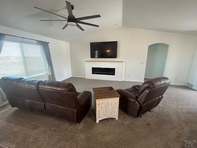 carpeted living room featuring visible vents, a fireplace, arched walkways, a ceiling fan, and vaulted ceiling